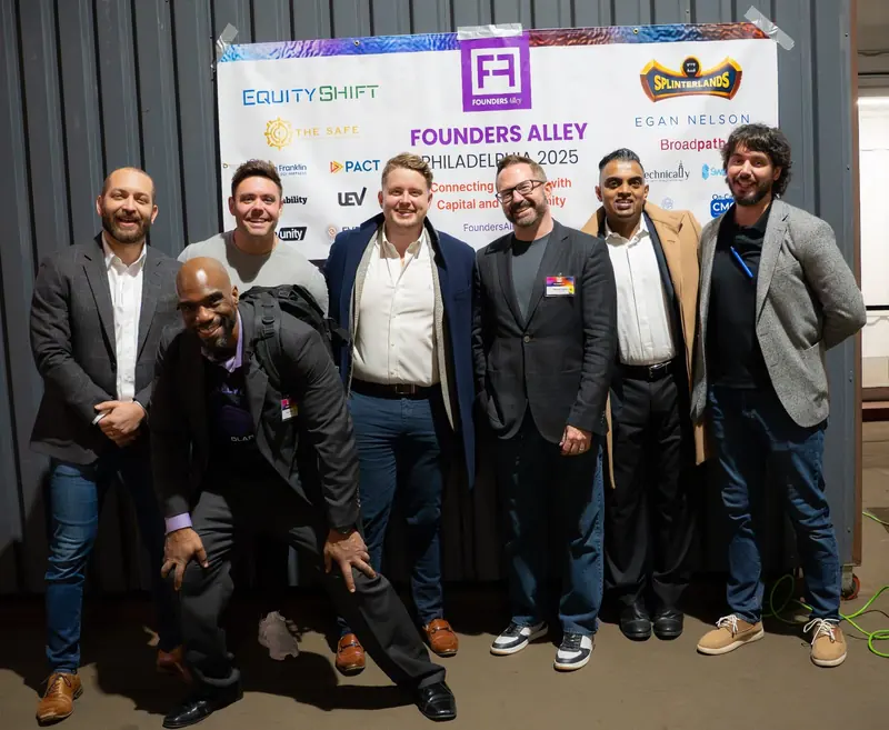 Speakers and organizers in front of the Founders Alley step-and-repeat banner